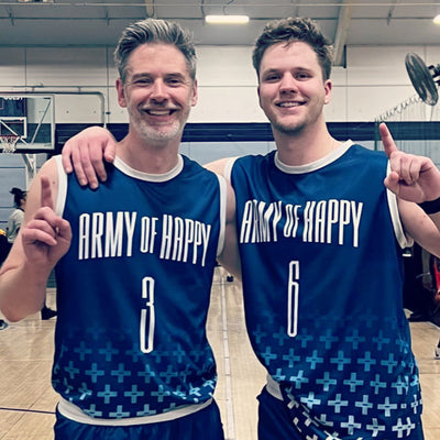 Two men wearing matching blue basketball jerseys with 'Army of Happy' text in a gymnasium.
