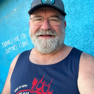 Man wearing a navy tank top with red and white text against a blue wall.