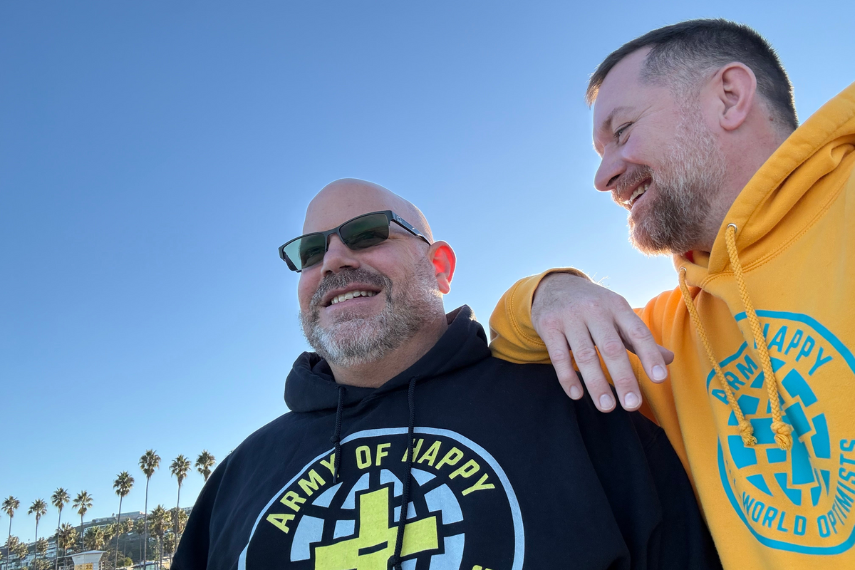 Two men wearing hoodies with visible branding on a beach.
