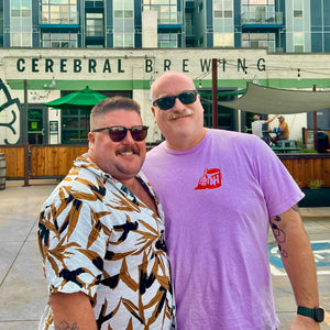 Two men posing in front of a building labeled 'Cerebral Brewing'. 